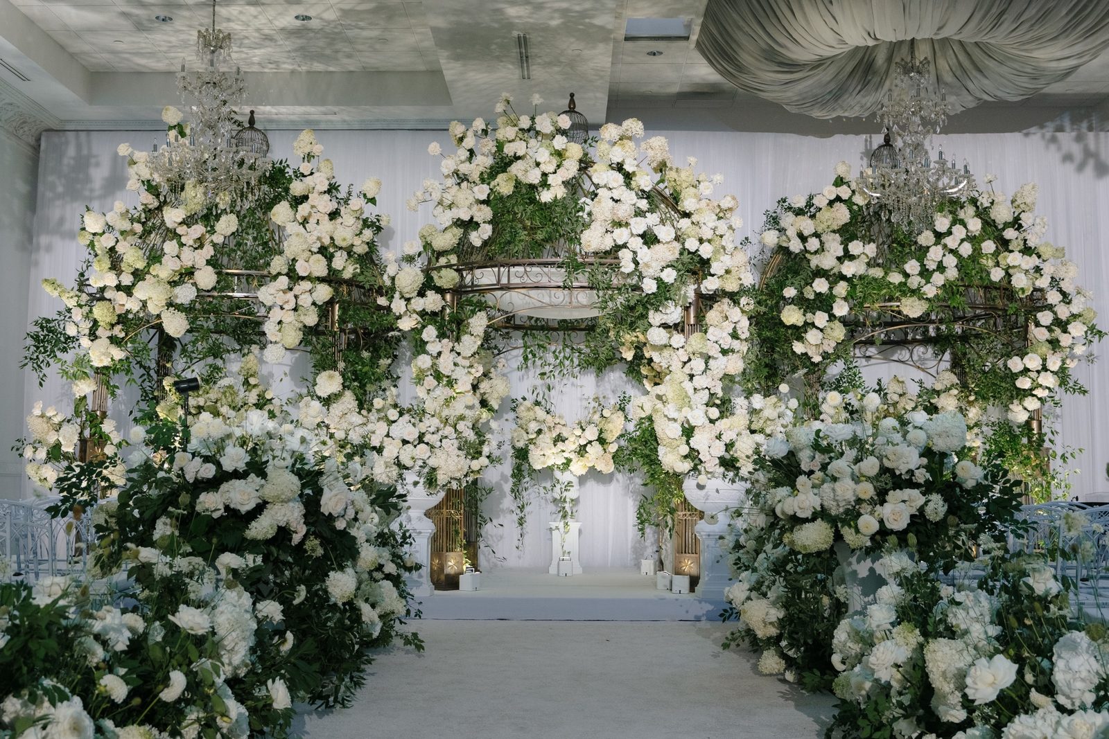The chuppah of white roses and greenery