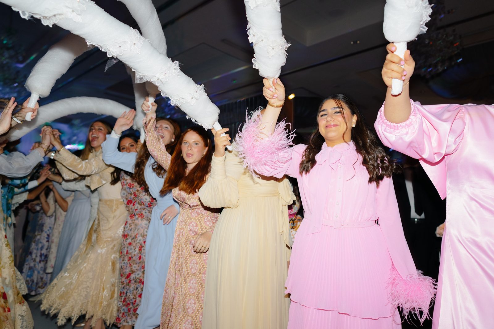 Guests holding feather arches for the bride