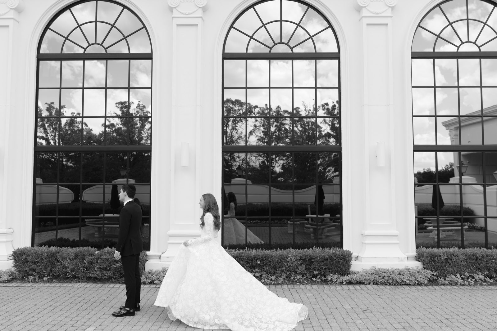 Black and white portrait of Atara and Ezra beneath the arched windows of The Addison Park