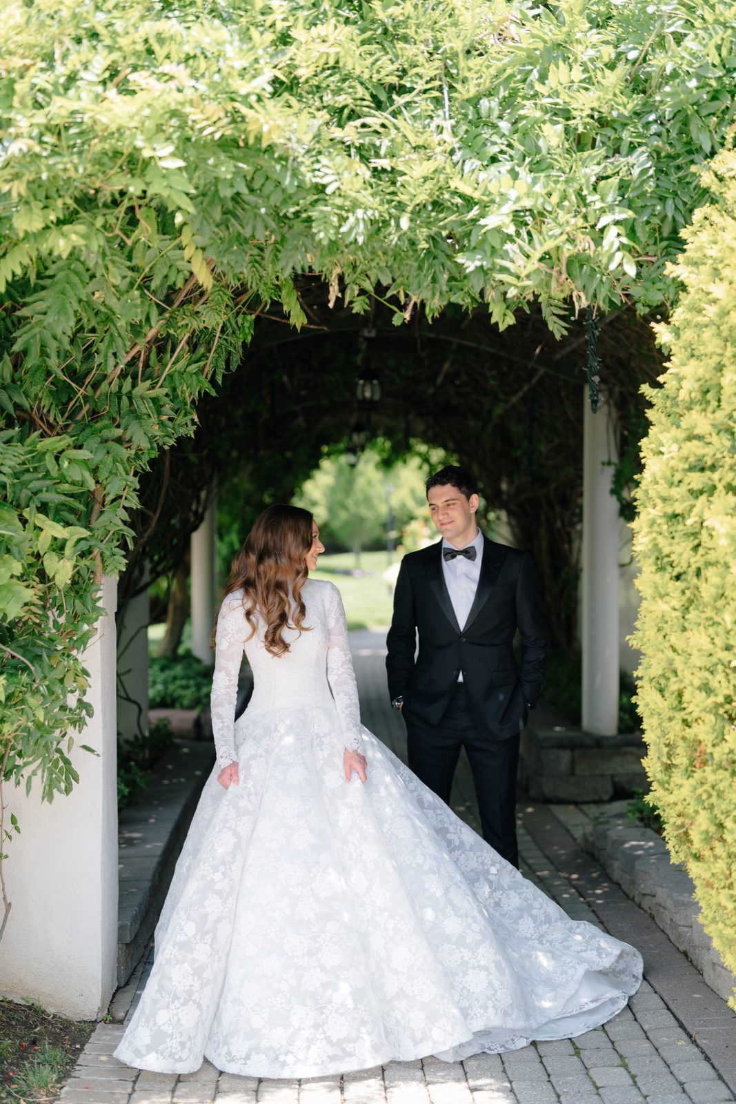 Atara and Ezra under the vine-covered arbor walkway at The Addison Park