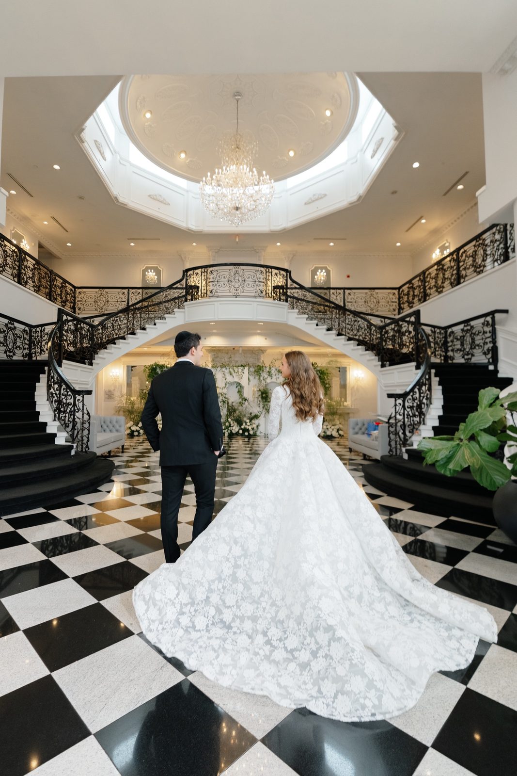 Atara crossing the black and white checkerboard foyer under the double staircase at The Addison Park