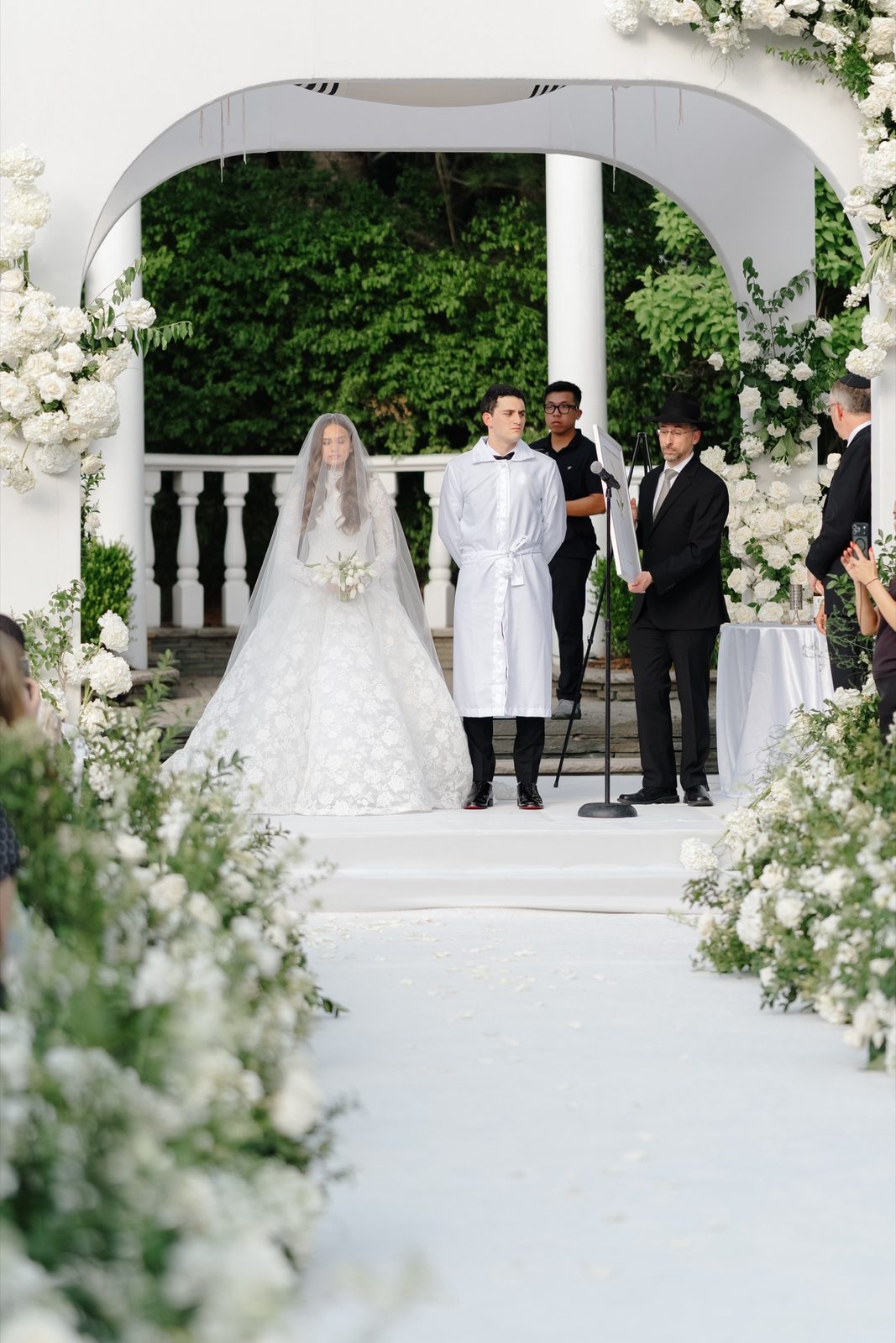 Atara and Ezra under the chuppah at the white garden pergola, The Addison Park