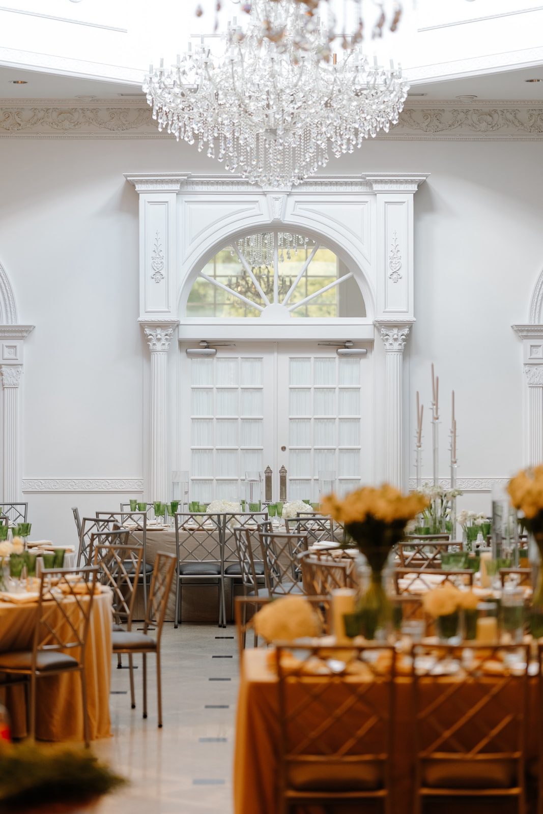 The reception room set with gold linens under a crystal chandelier at The Addison Park