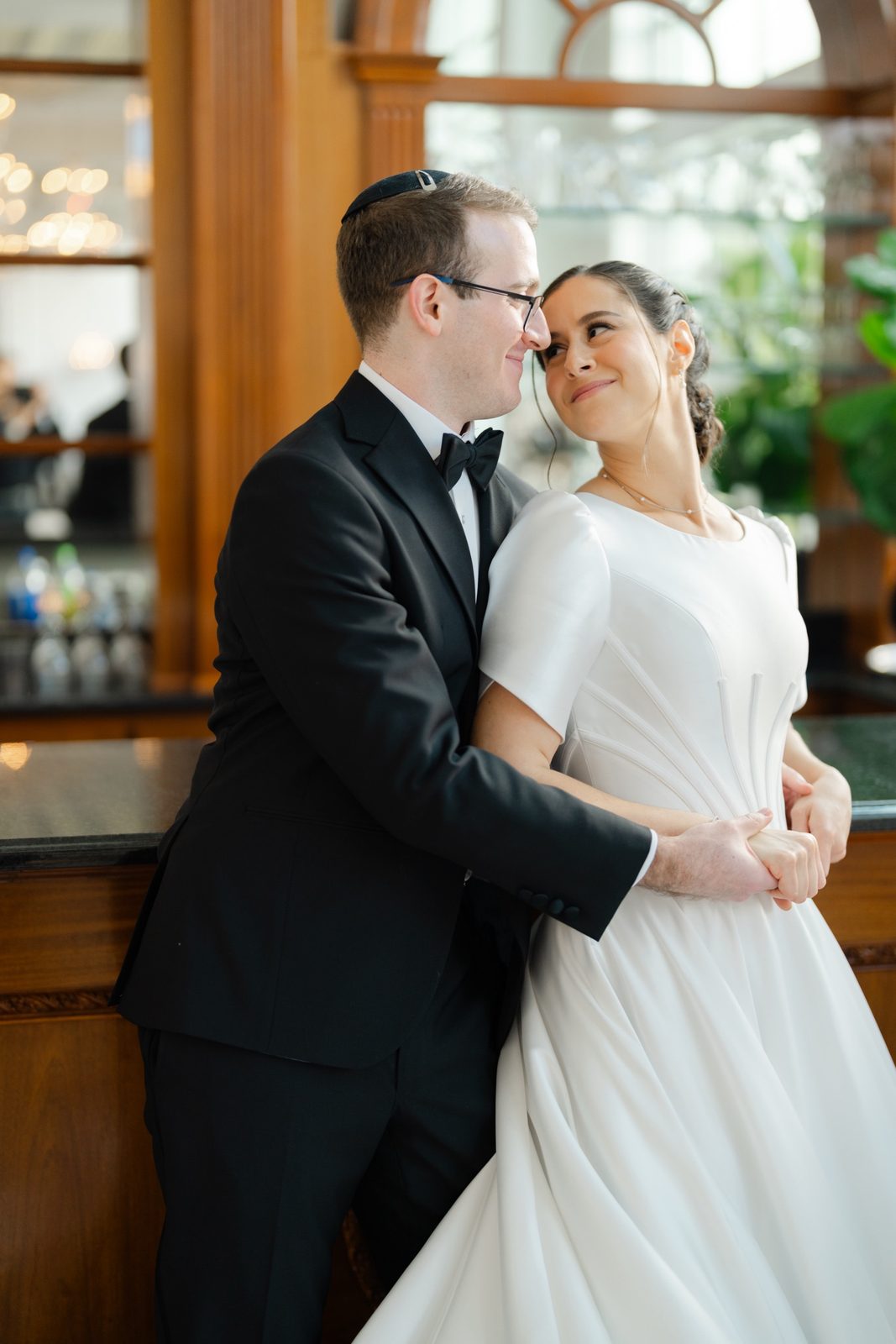 Kayla and Gabriel at the wood-paneled bar with its arched window