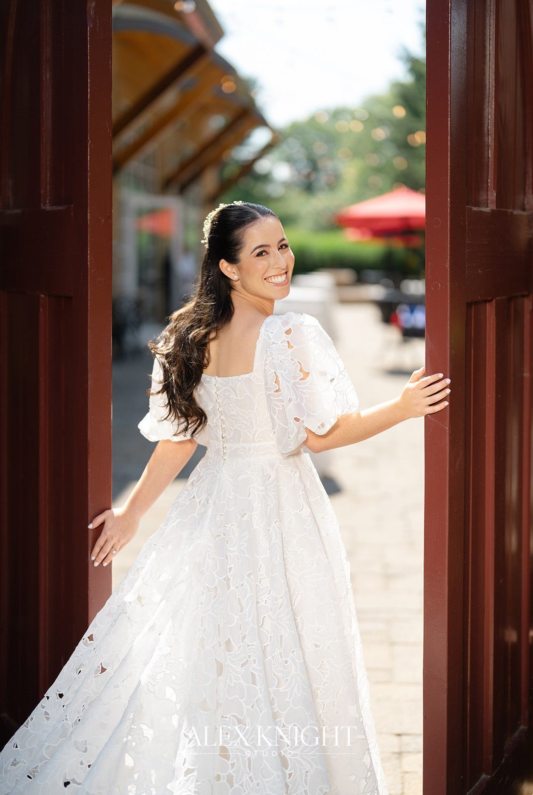Aline stepping through the red doors into the courtyard