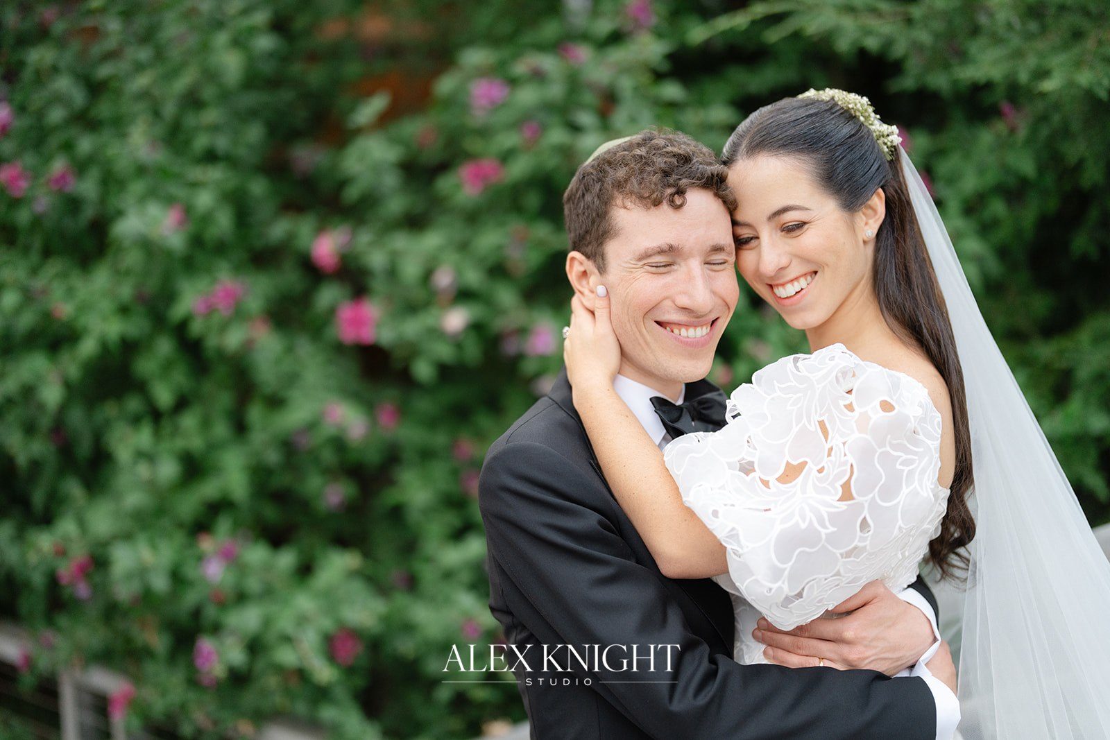 Aline and Tyler laughing together against the garden greenery
