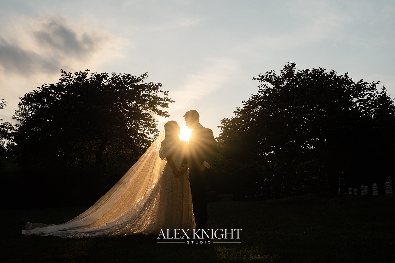 Aline and Tyler silhouetted against the sunset over the treeline