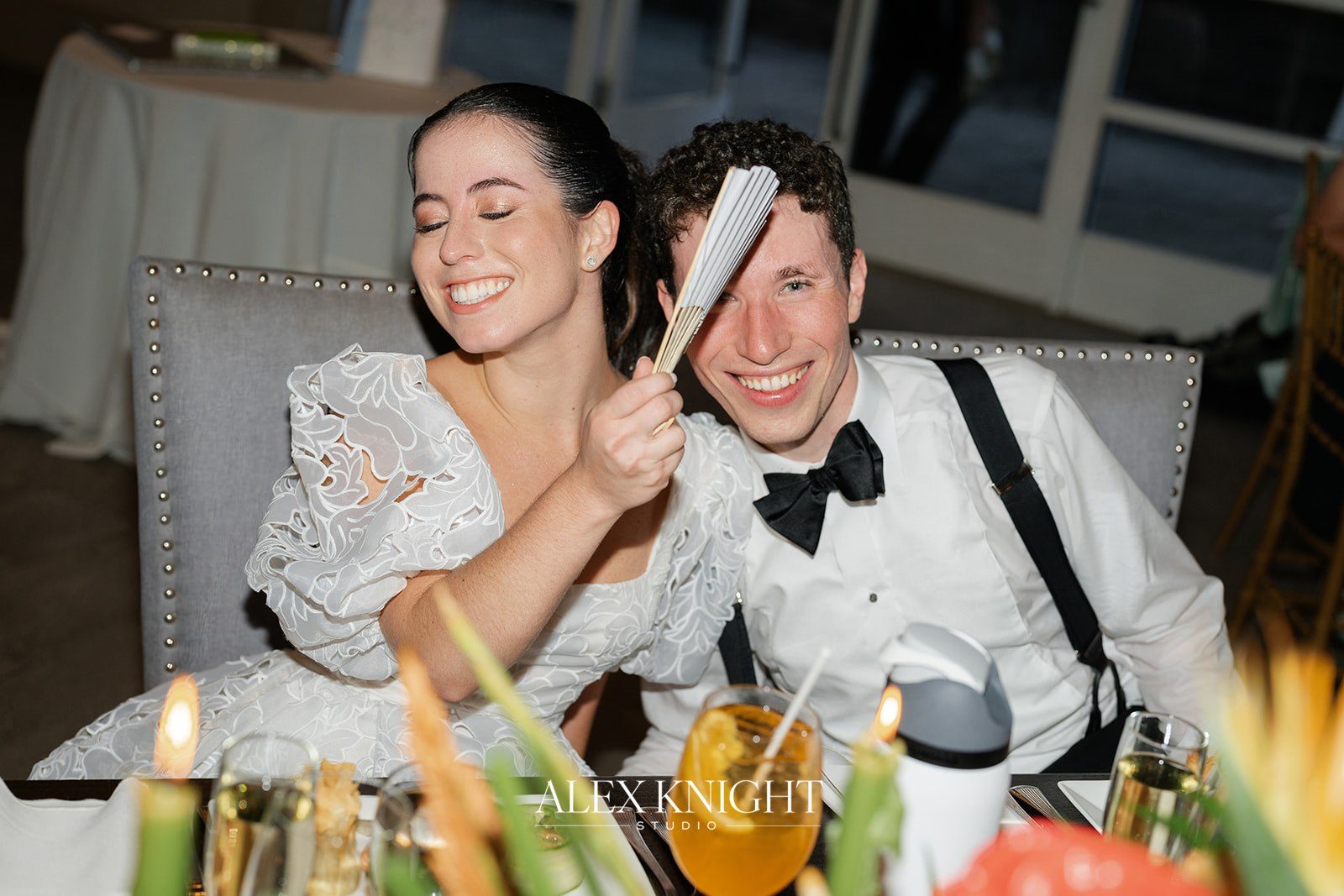 Aline and Tyler laughing at their sweetheart table