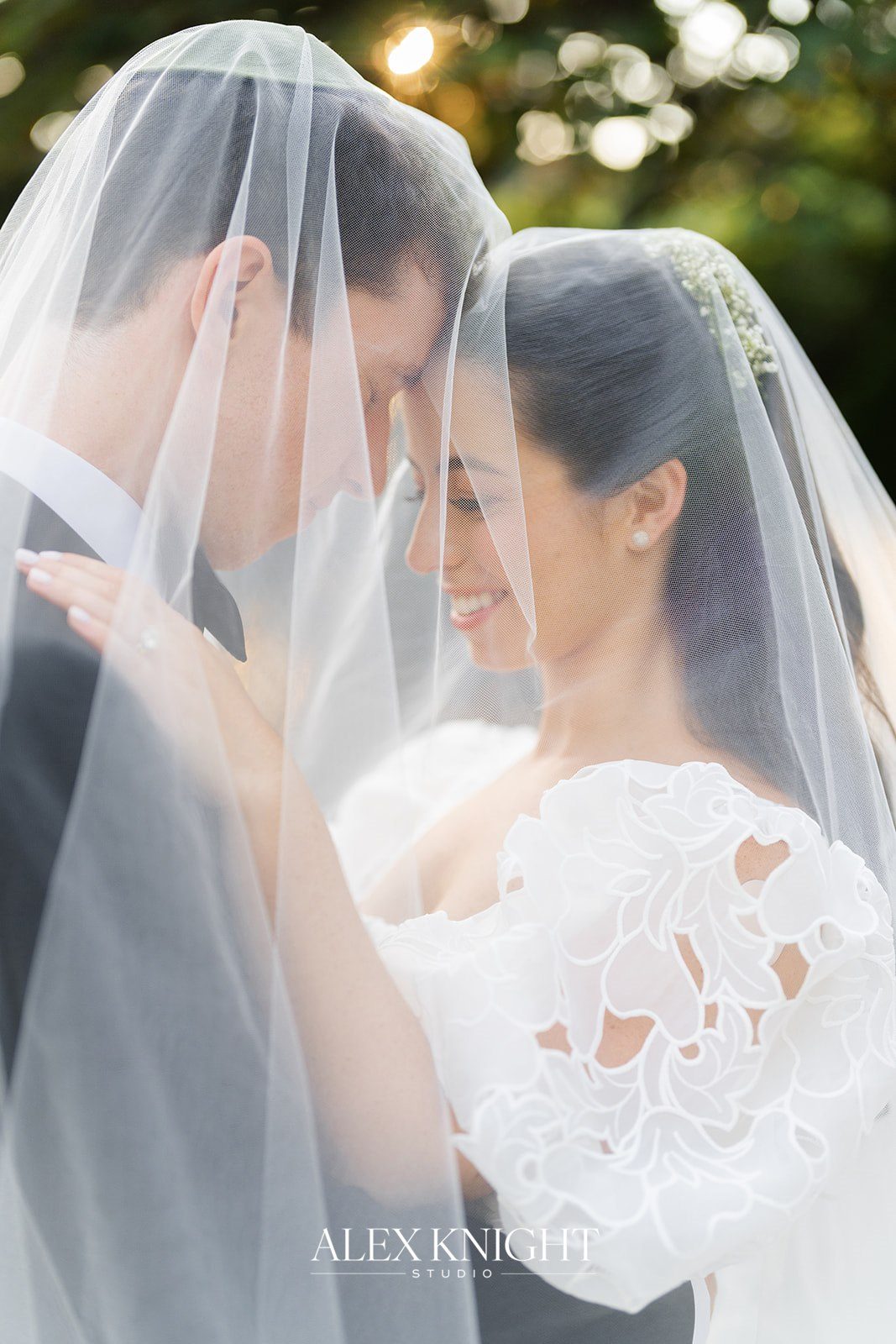 Aline and Tyler under her veil in the garden light