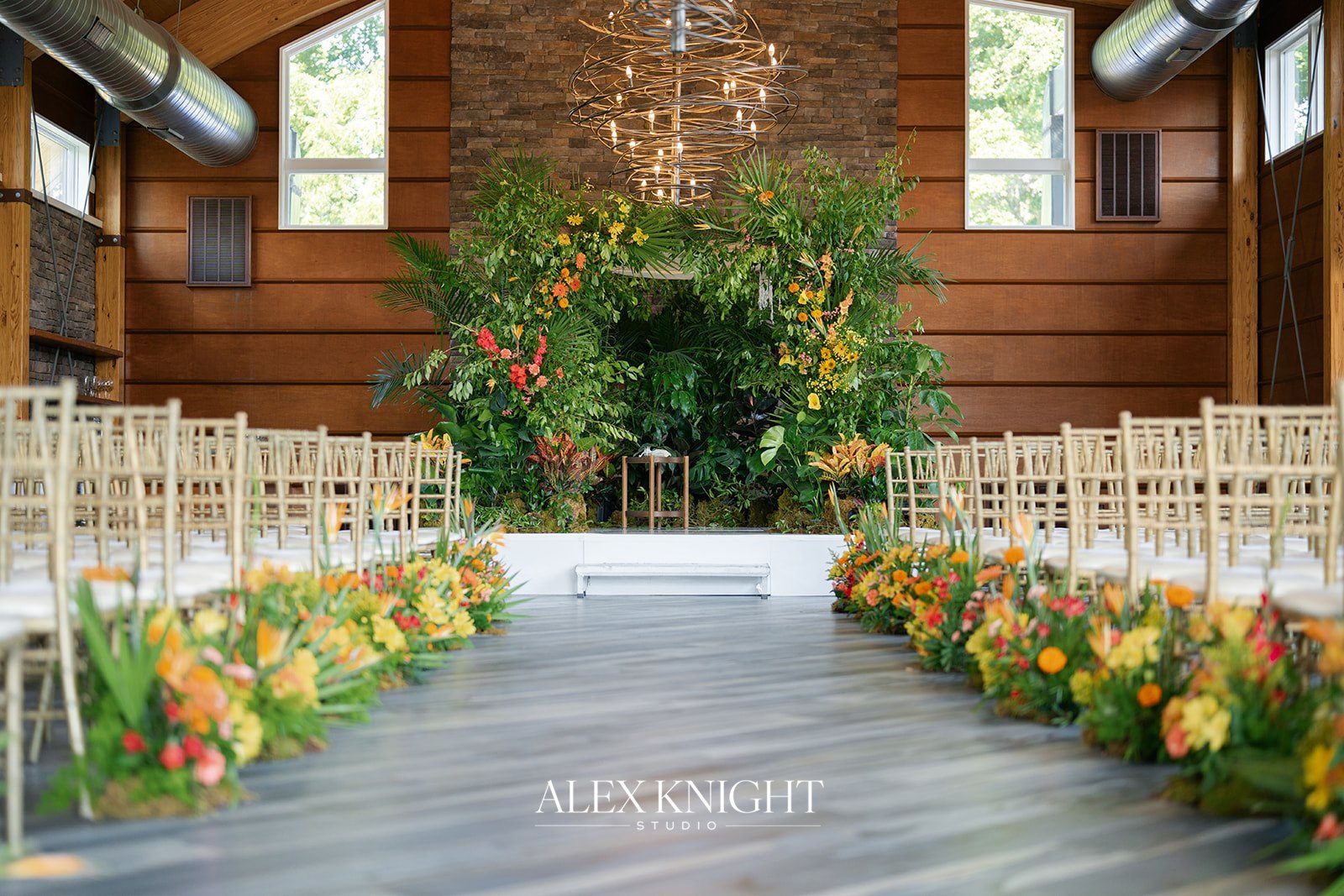 The ceremony set in the Lodge at Stone House, an orange and yellow floral chuppah in front of the stone fireplace
