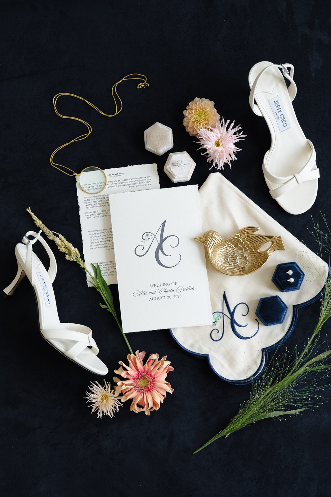 Bridal details: monogrammed clutch, white heels and dahlias on navy velvet