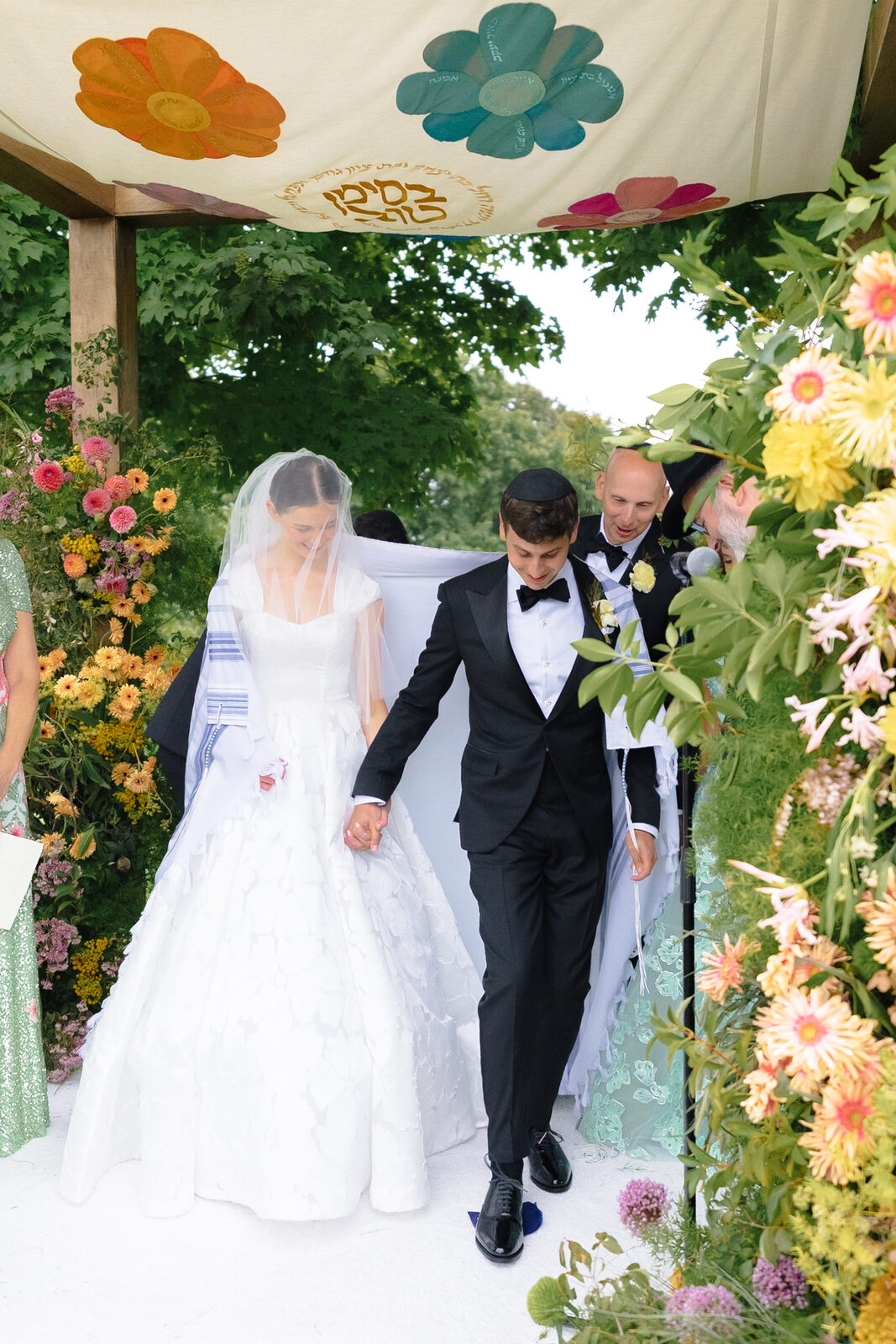 Allie and Charlie walk back up the aisle beneath the painted chuppah canopy