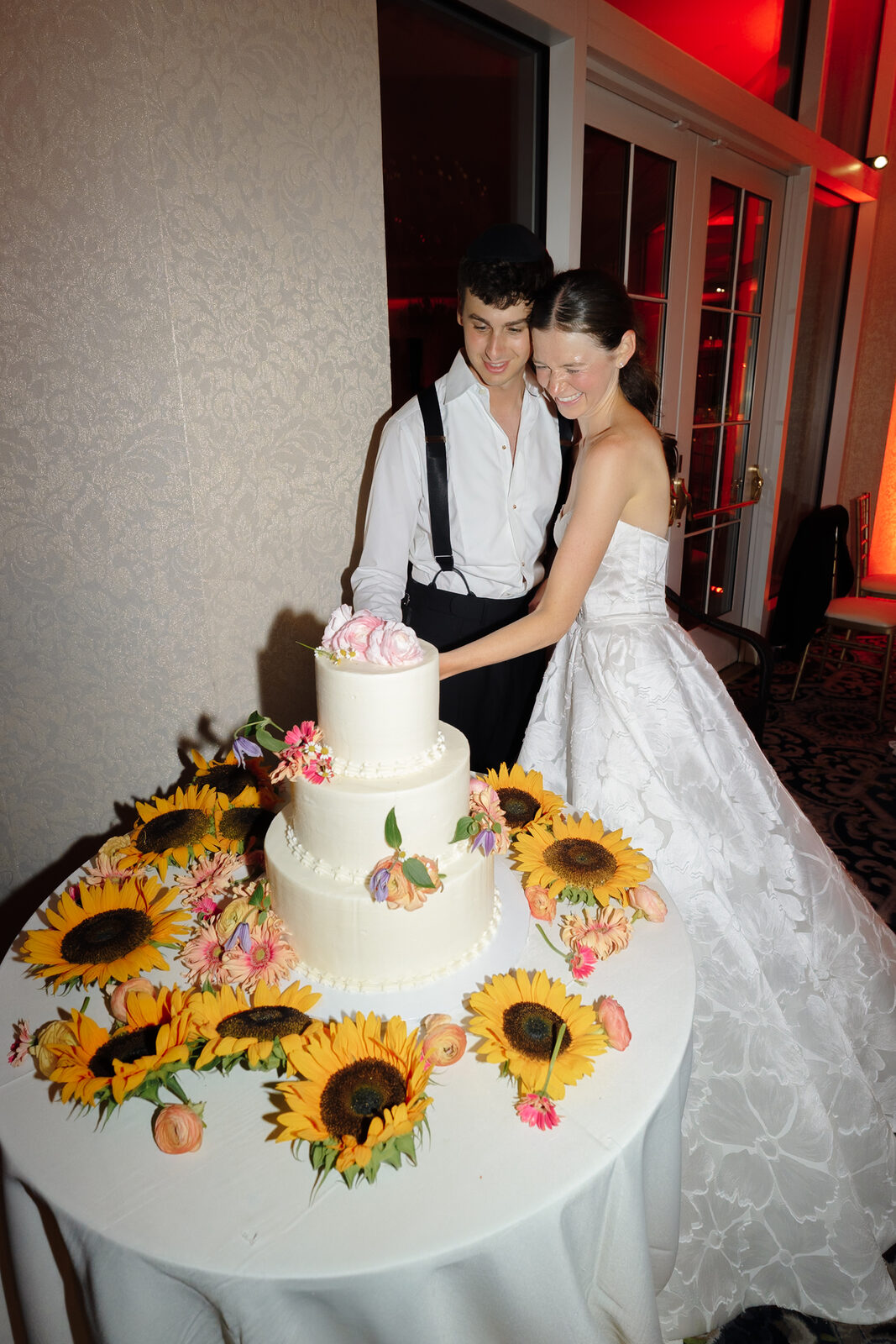 Allie and Charlie cutting a cake wrapped in sunflowers