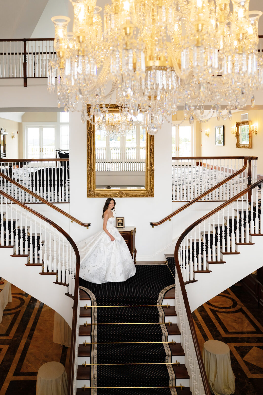 Allie on the grand staircase beneath the chandelier at Trump National Westchester