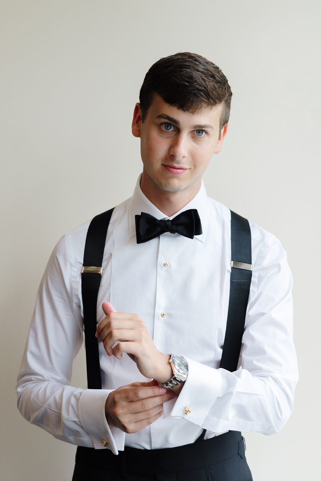 Charlie fastening his cufflinks in suspenders before the tuxedo goes on