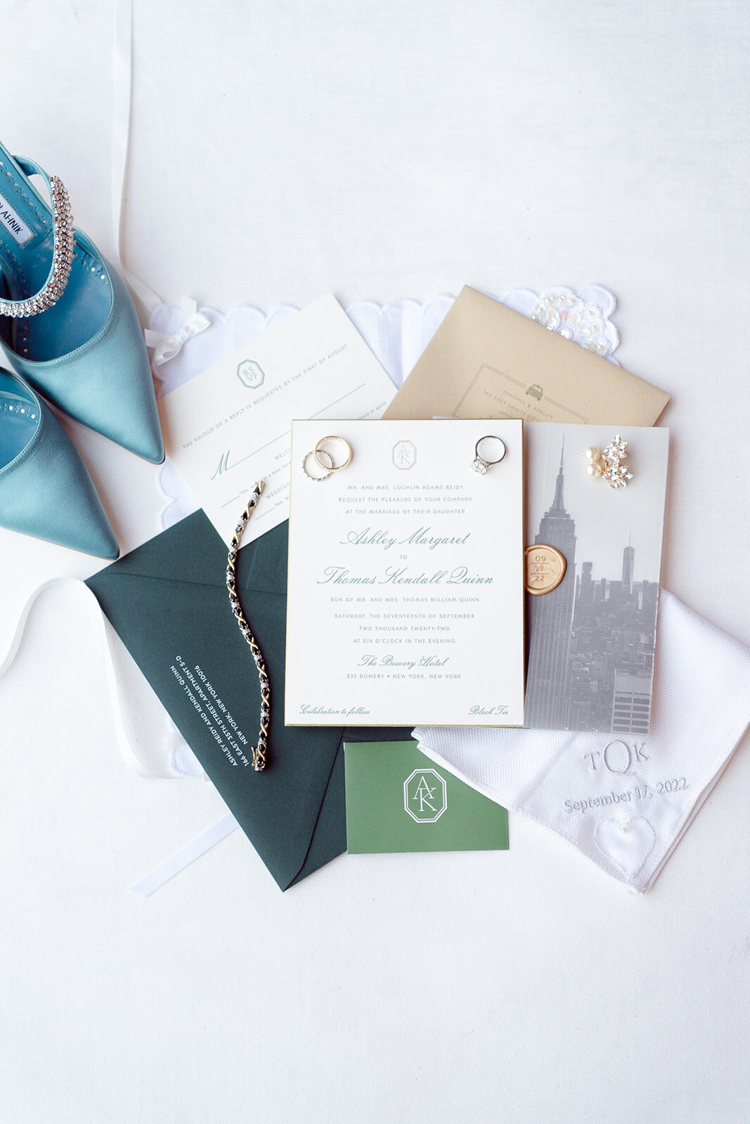 The invitation suite laid out with robin’s egg blue Manolo Blahnik heels and a green envelope