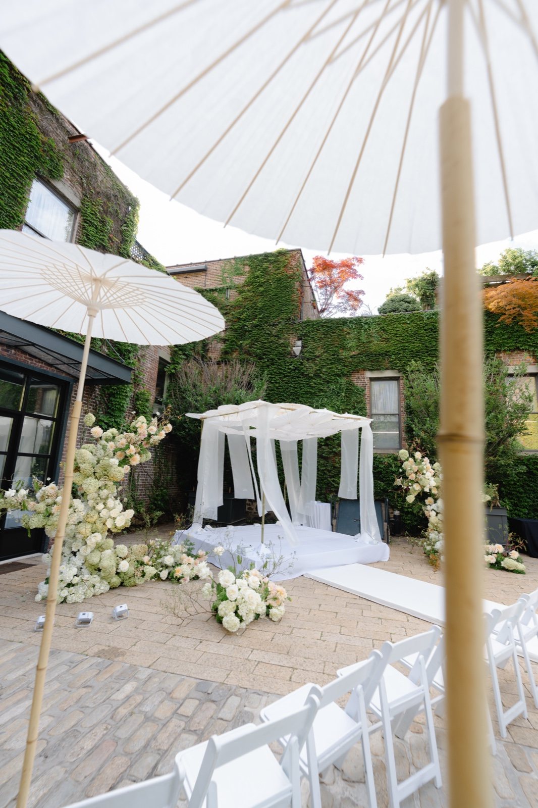 The chuppah in the courtyard under white parasols
