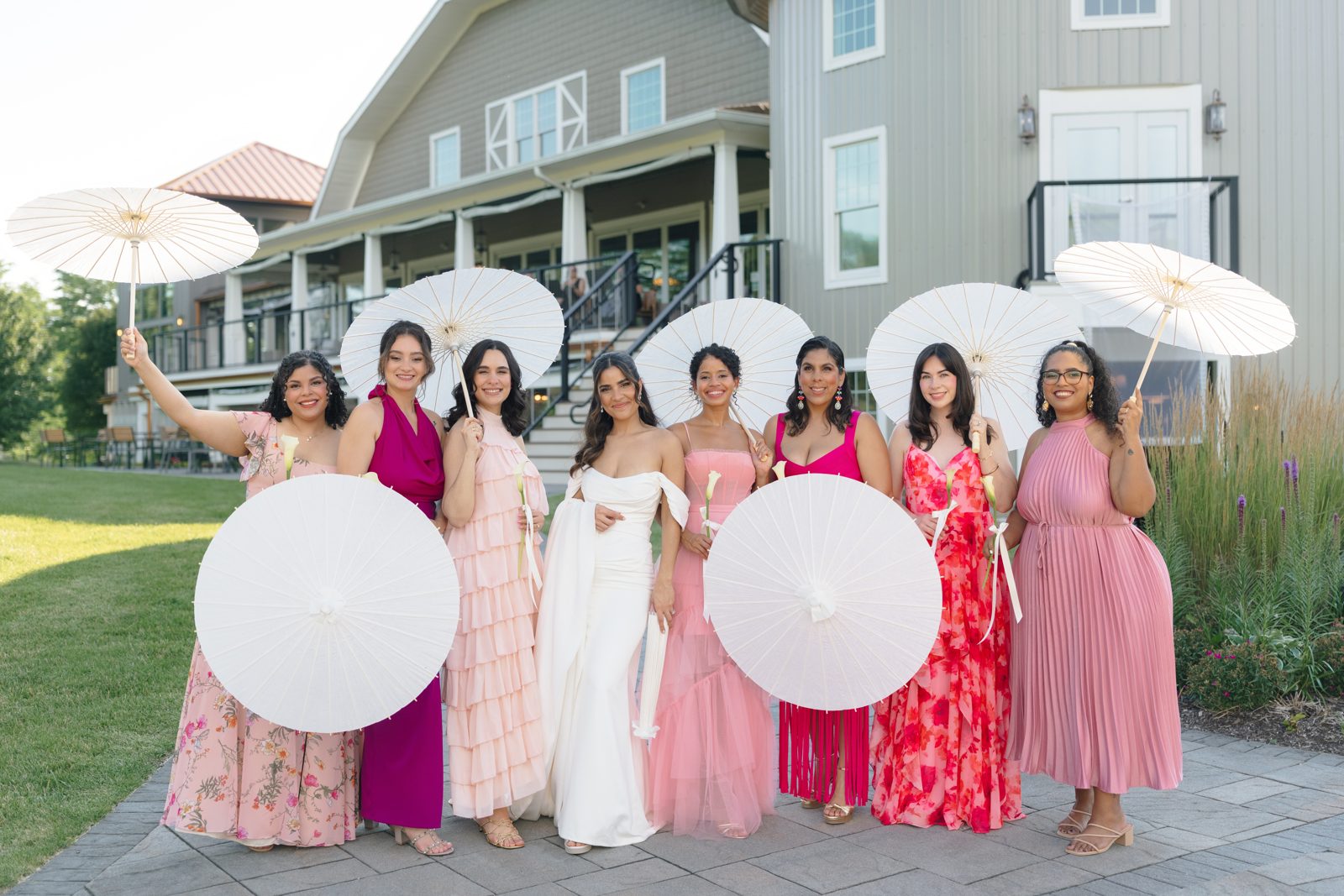 The bridal party raise their parasols on the lawn