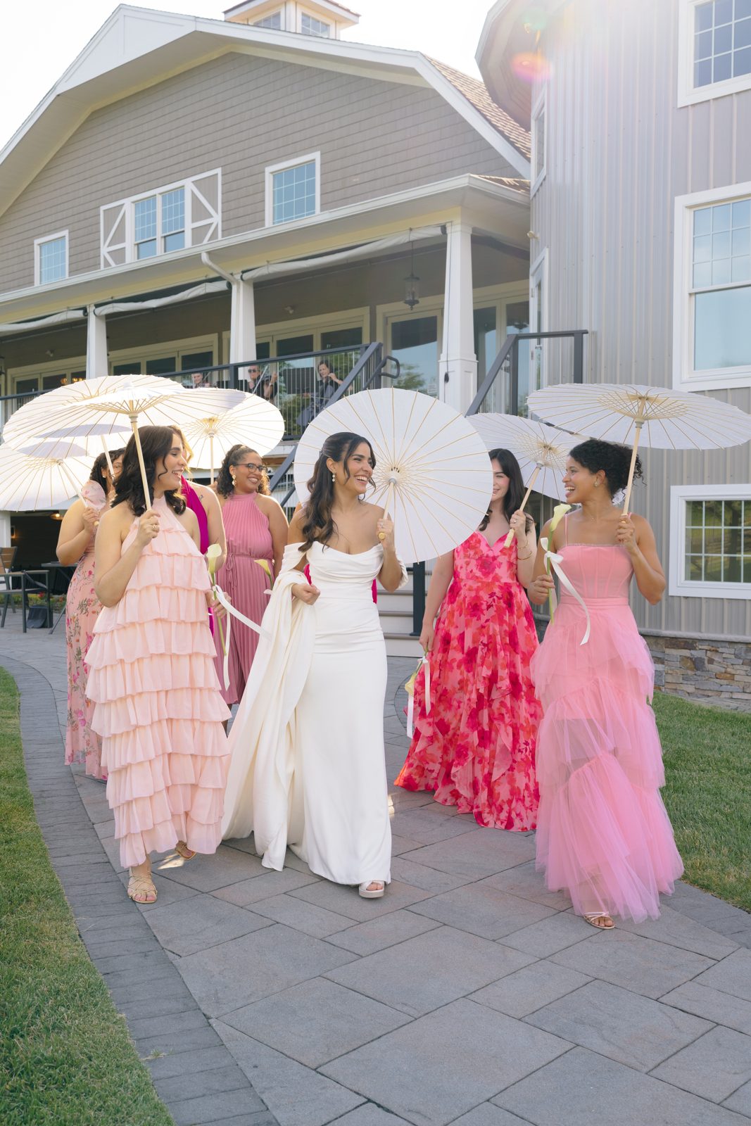 Bridesmaids in shades of pink with white parasols at Bear Brook Valley