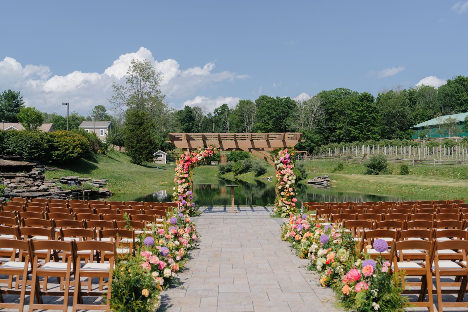The wooden ceremony pergola at Bear Brook Valley dressed in vivid pink and coral florals