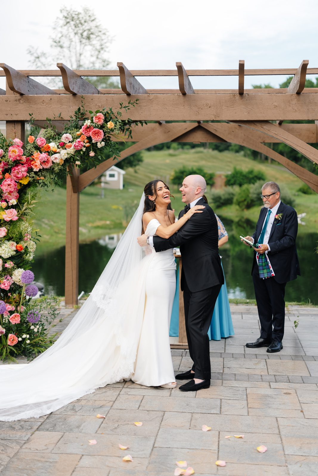 The outdoor ceremony at Bear Brook Valley under a pergola of pink and coral florals