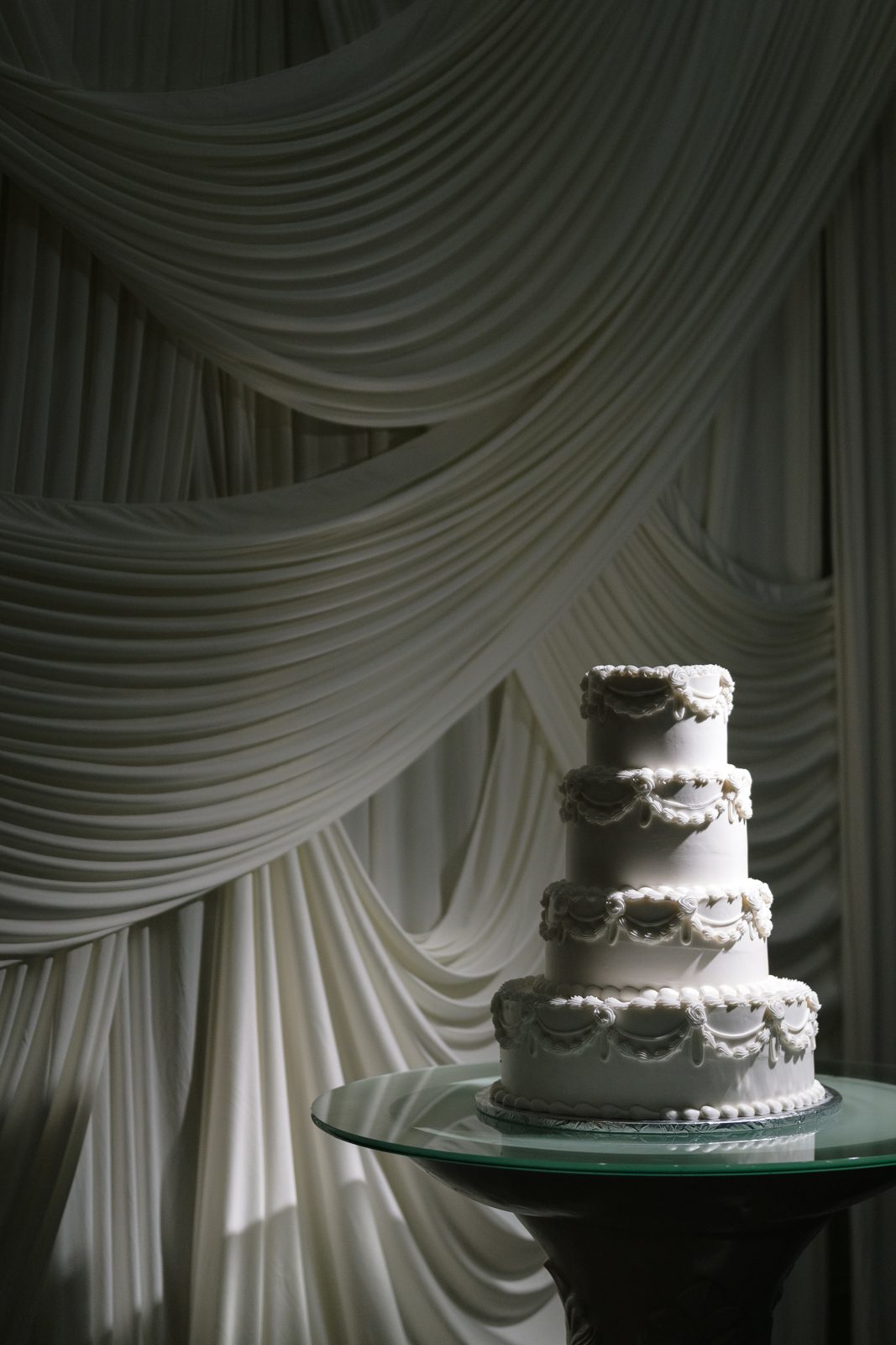 The tiered wedding cake against a softly draped backdrop