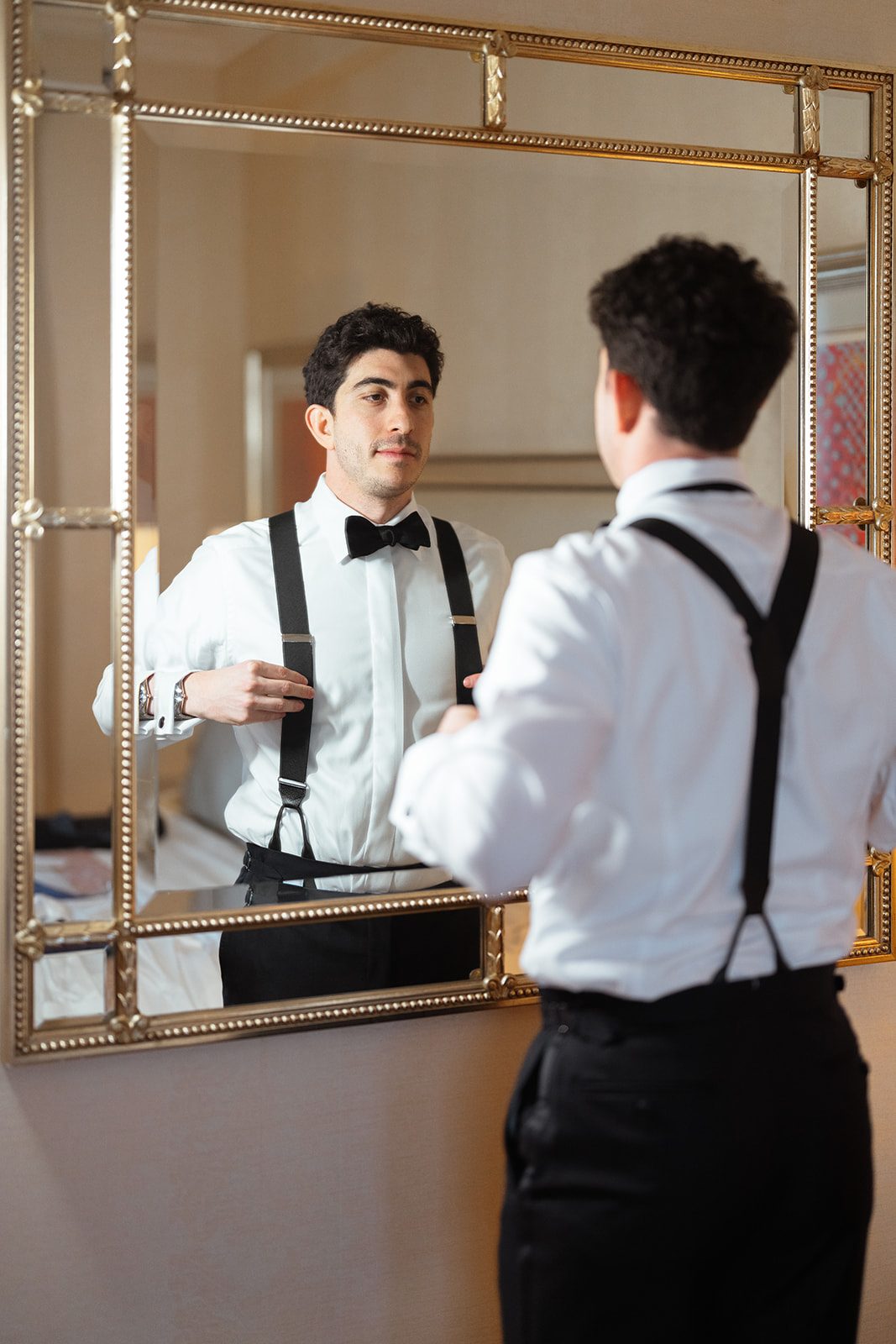 Ben getting ready in the mirror with his groomsman