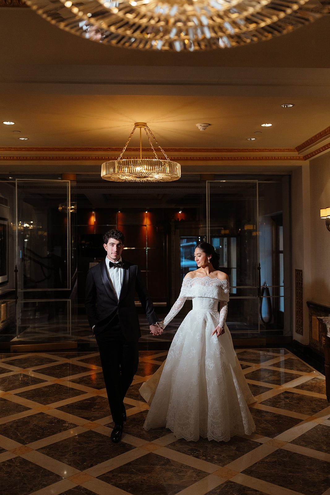Dori and Ben hand in hand in the lobby of The Pierre