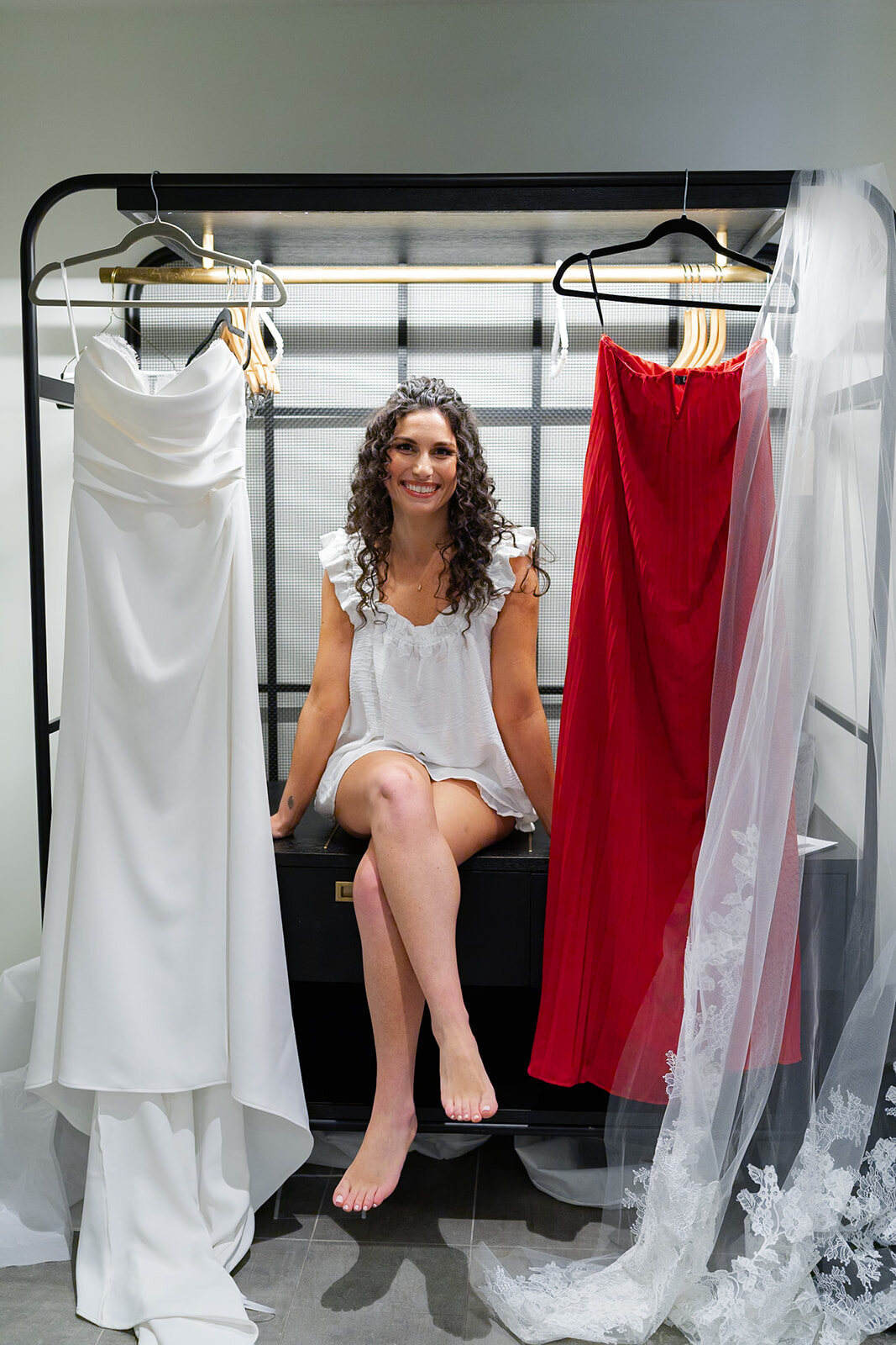 Ellie sitting between the gowns on the rack