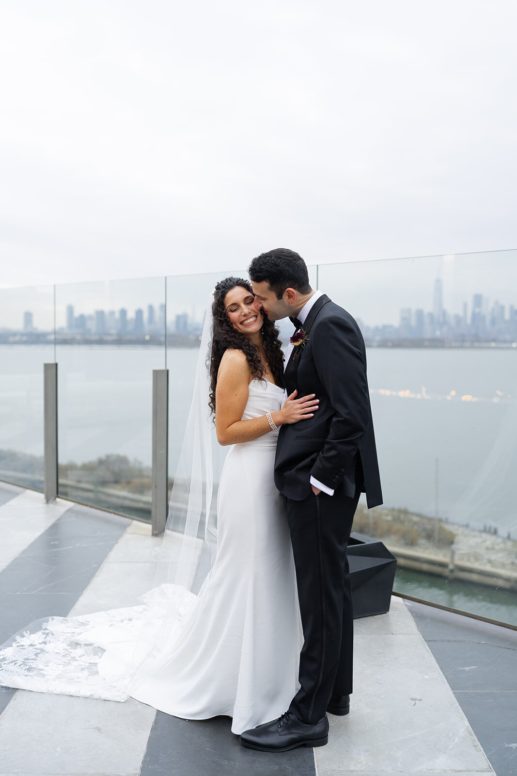 Ellie and Harrison by the glass railing with the Manhattan skyline