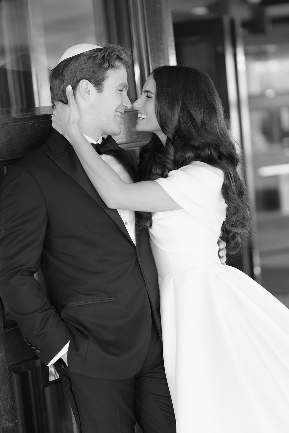 Black and white portrait of the bride and groom together in the light of the club windows.