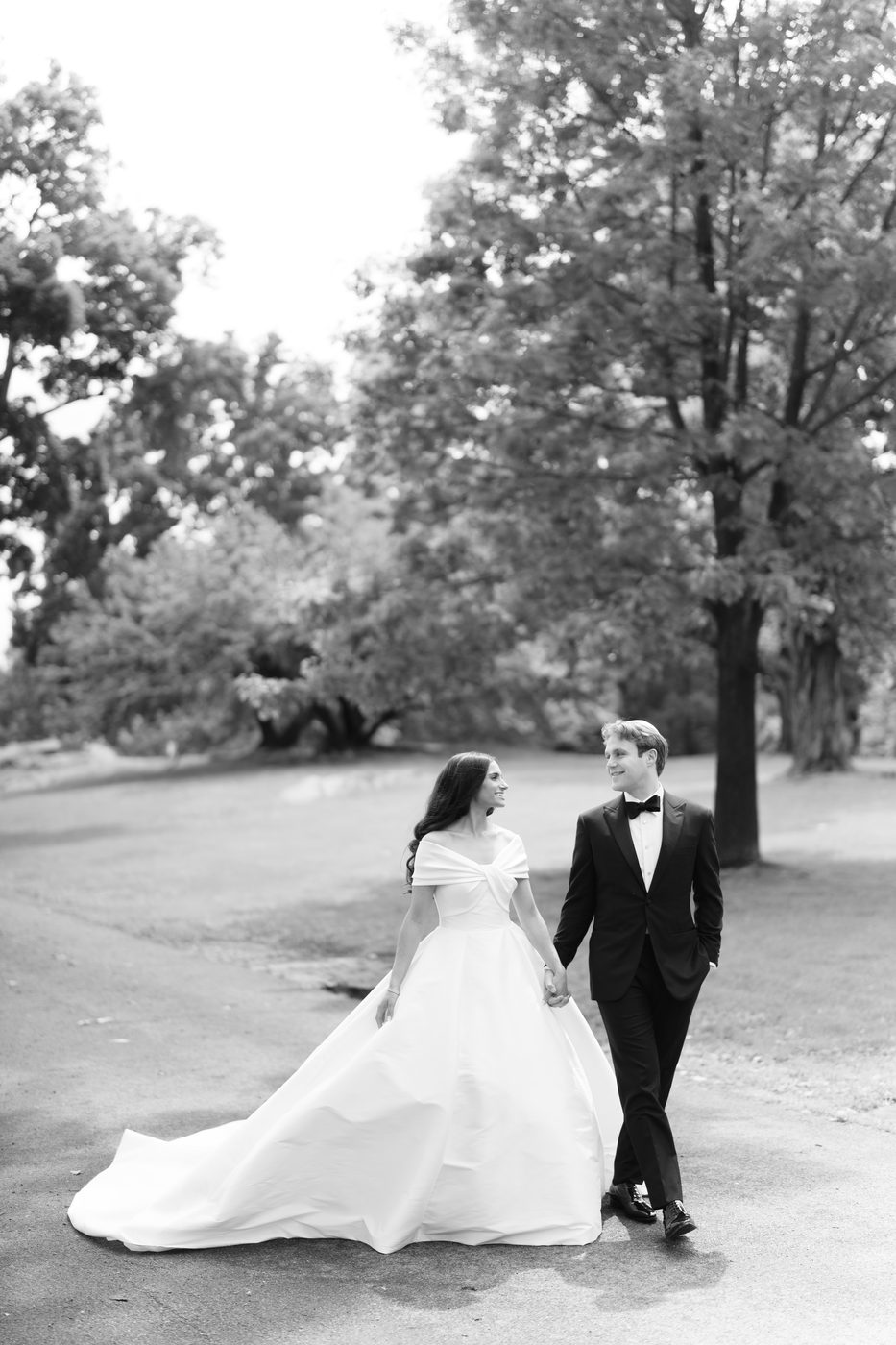 Black and white photo of the bride and groom walking hand in hand beneath the old trees on the island.