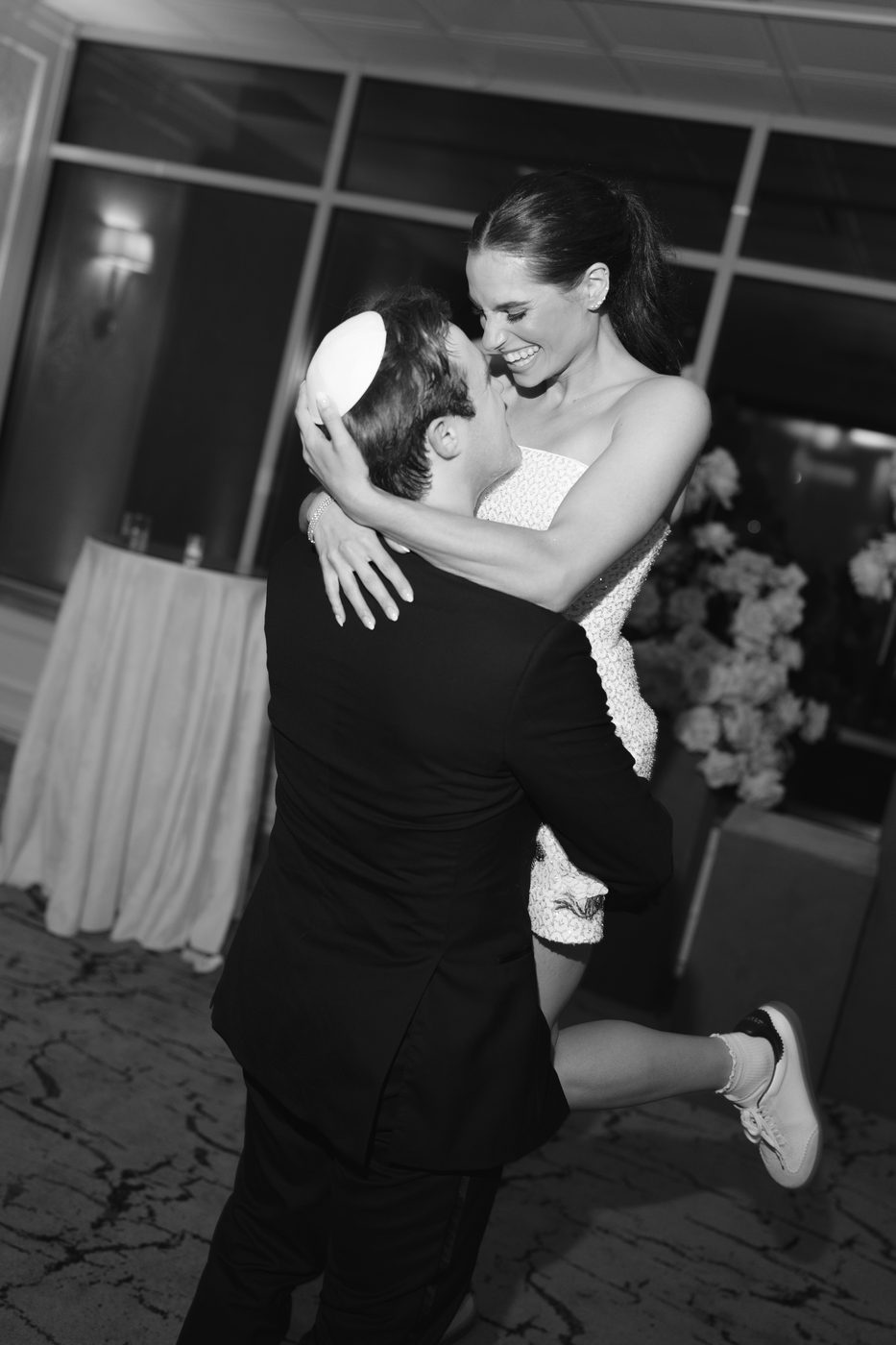 Black and white photo of the groom lifting the bride off the floor at the end of the night.