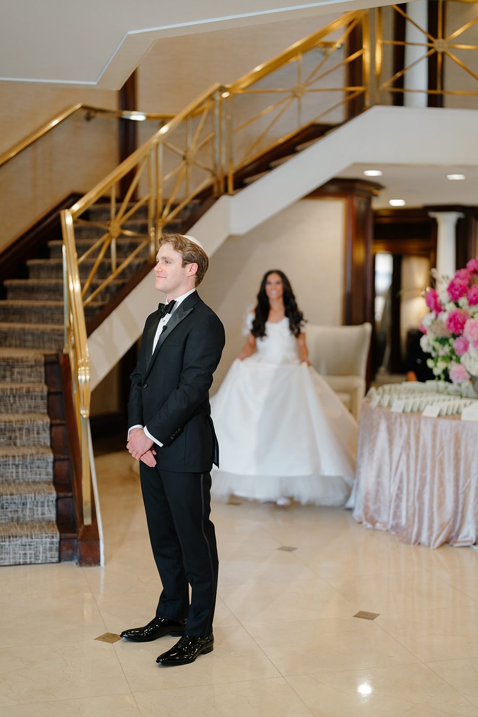 The groom turns to see the bride for the first time on the grand staircase at Glen Island Harbour Club.