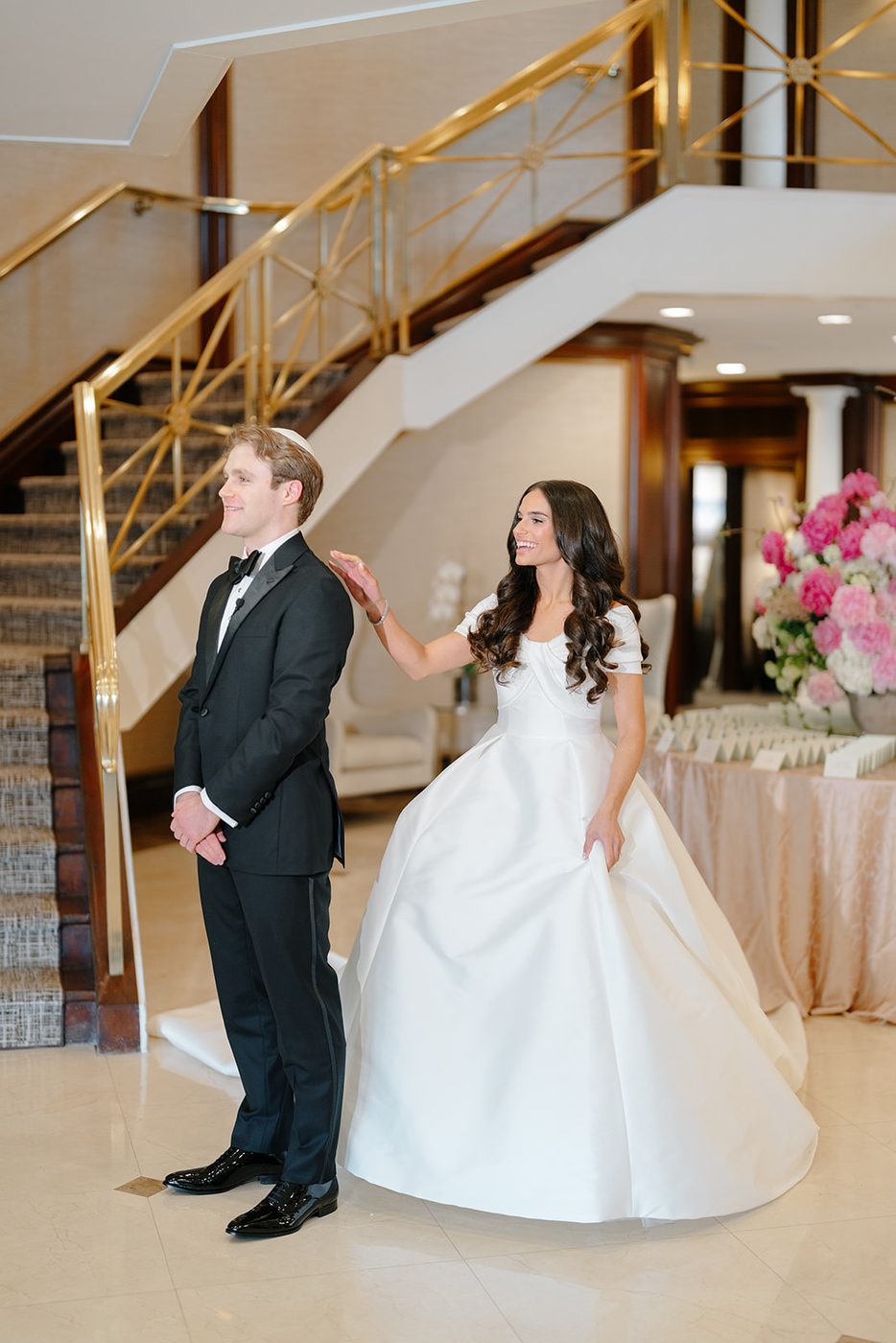 The bride and groom reach for each other at the foot of the staircase during their first look.