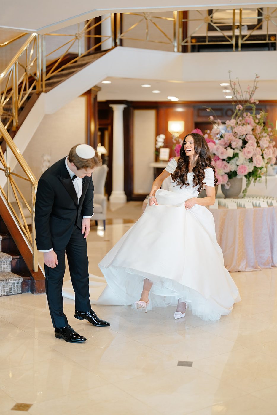 The groom waits at the bottom of the grand staircase as the bride comes down for their first look.