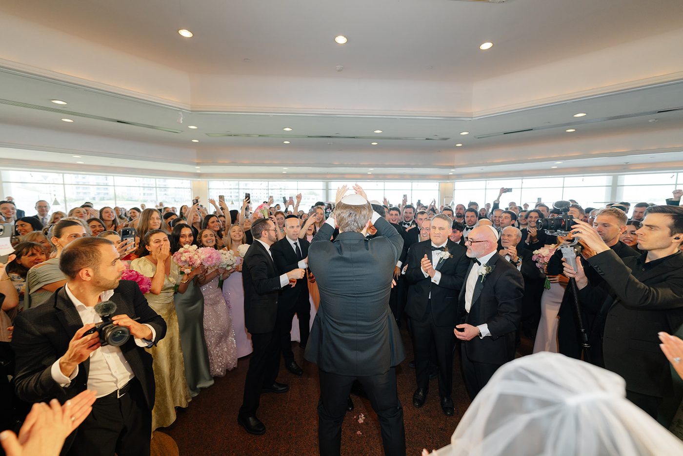 The hora in full swing, the bride's veil sweeping through a crowd of dancing guests.