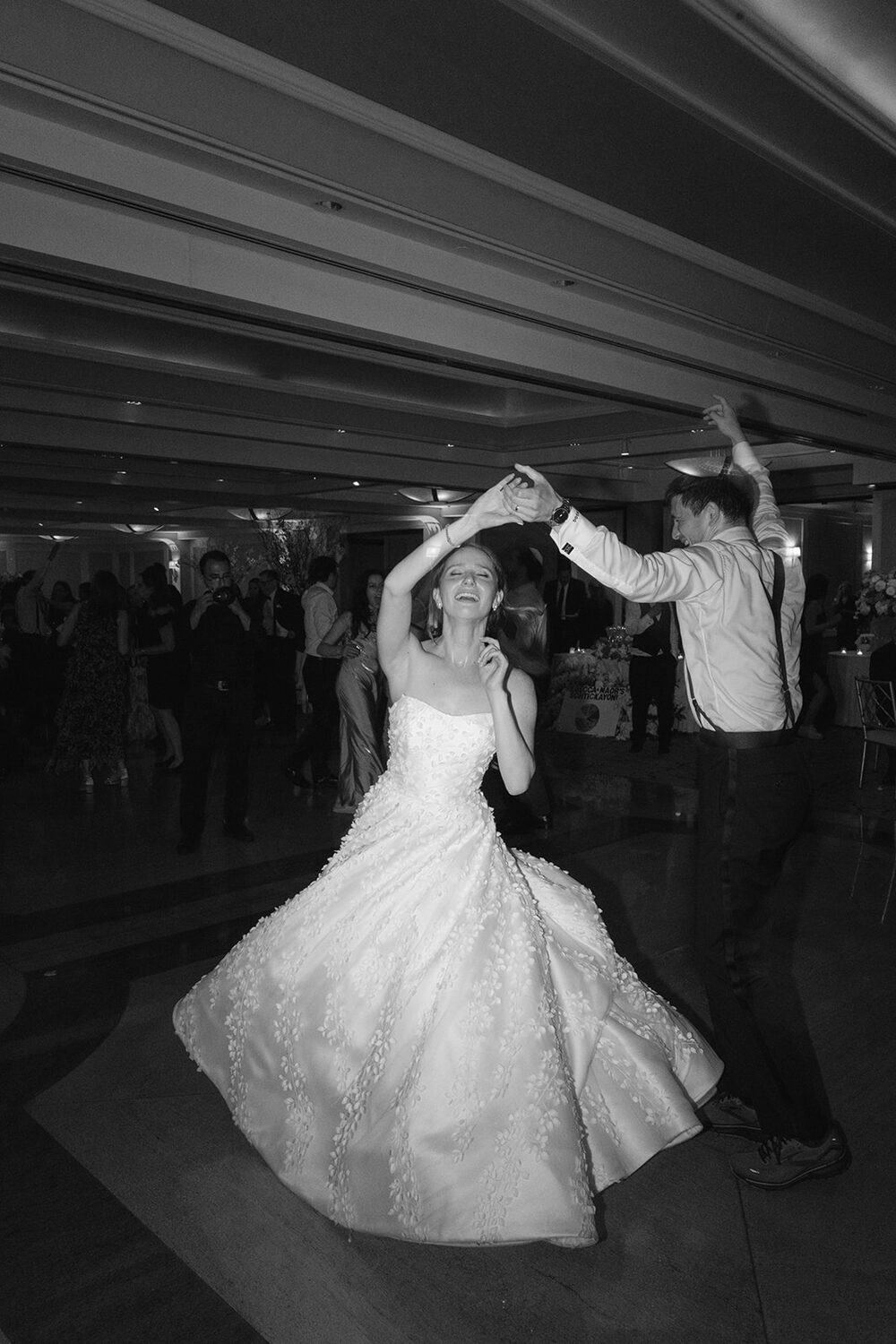 The groom twirls his bride in a black and white first-dance frame.