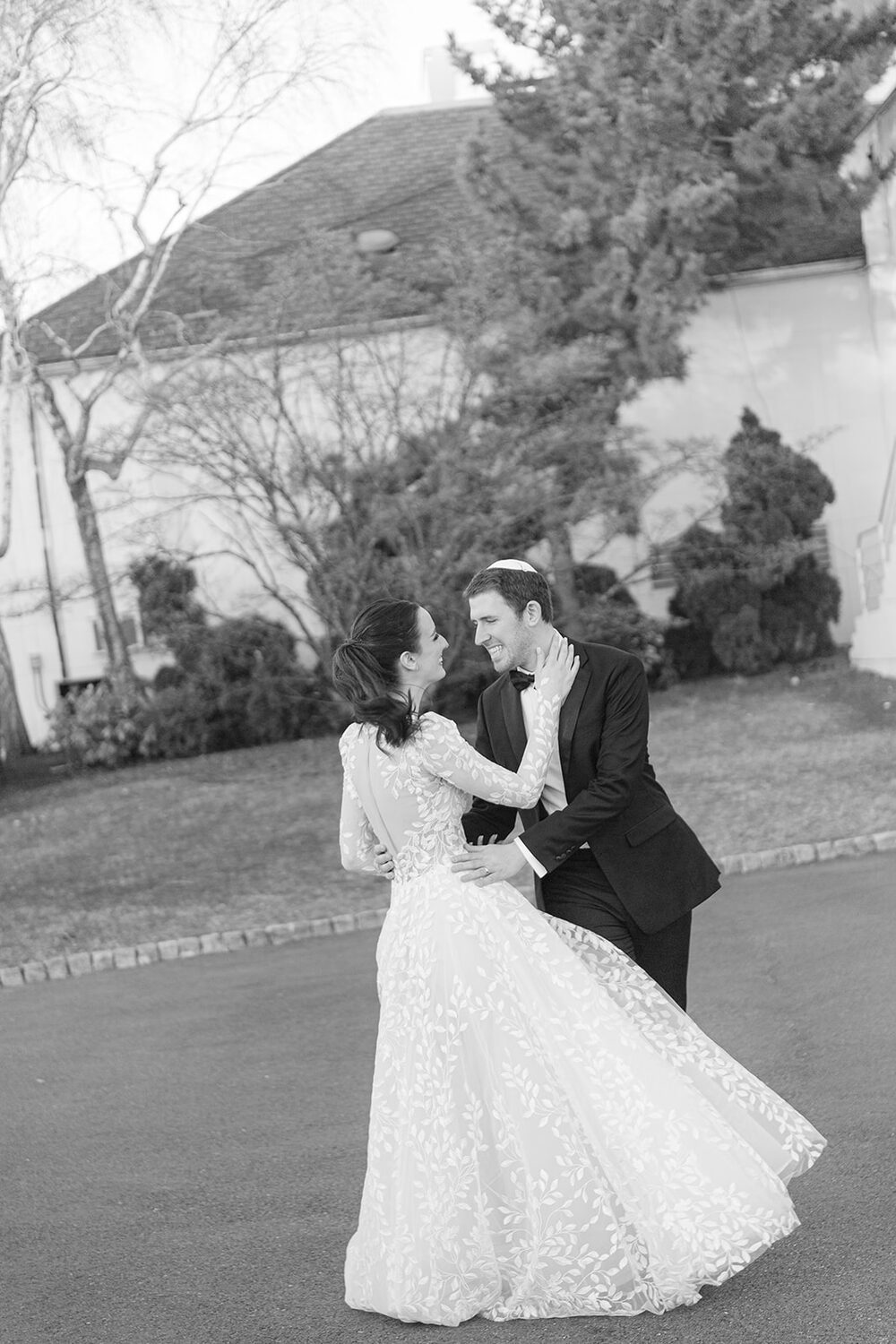 The couple dips into a dance move outdoors in black and white.