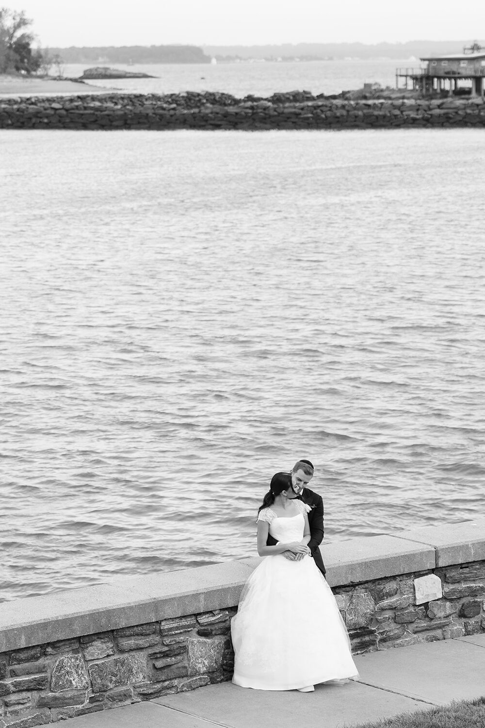 A black and white portrait at the seawall overlooking the water.