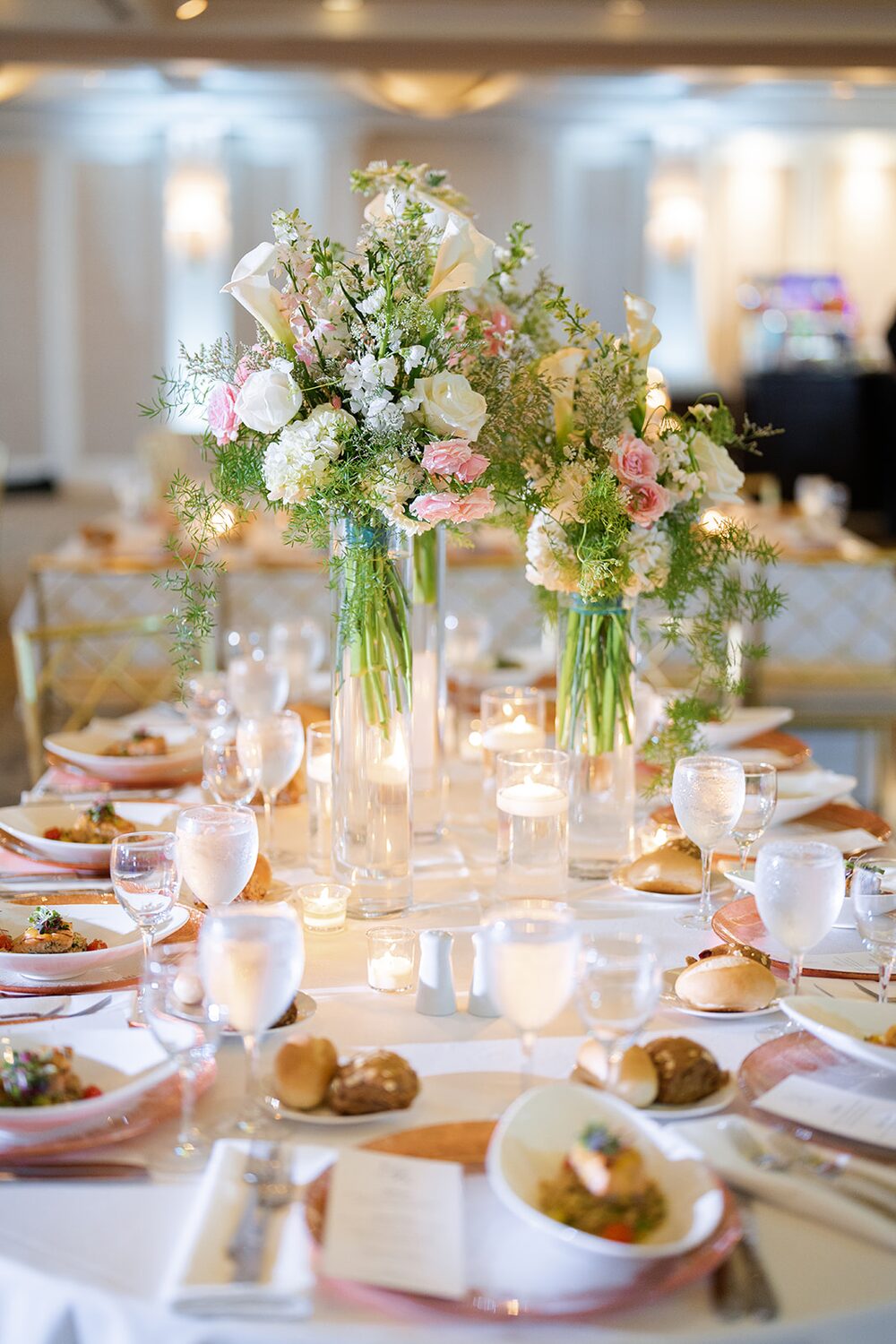 Blush garden-style centerpieces and candlelight dress the reception table.
