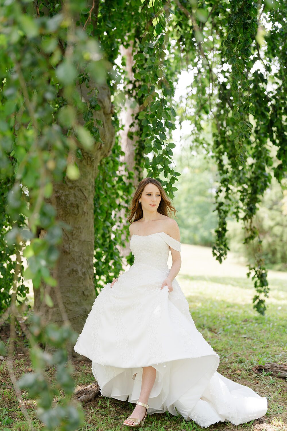 The bride stands beneath a curtain of willow branches on the island's lawn.