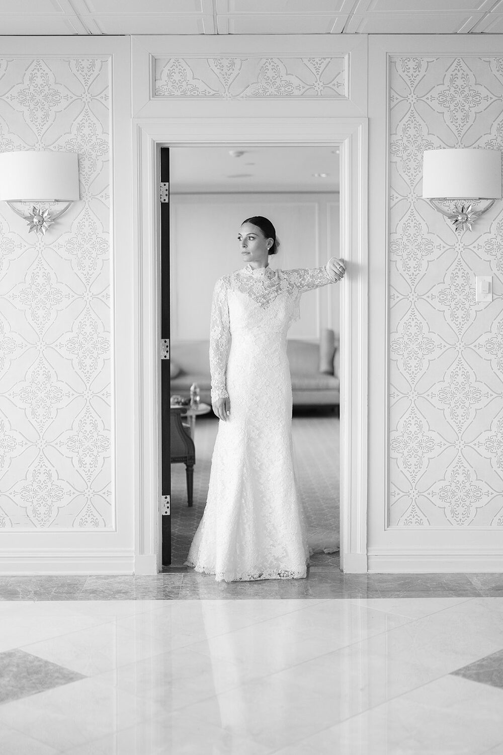The bride stands framed in a white paneled doorway before the ceremony.