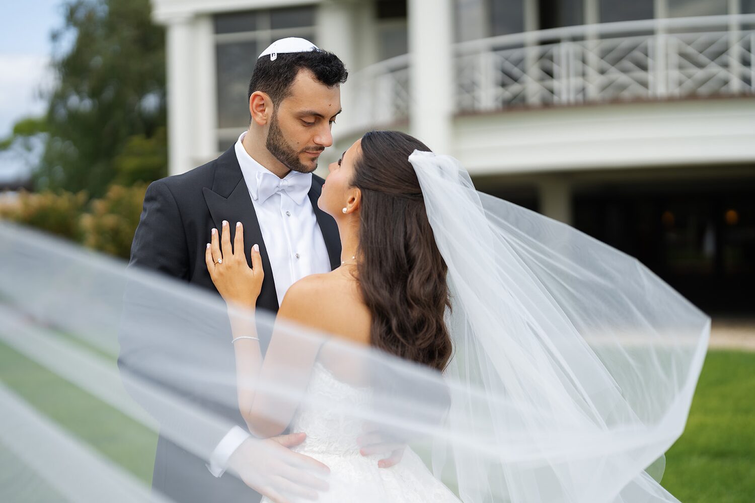 Wrapped together in her flowing cathedral veil, the couple shares a close kiss.