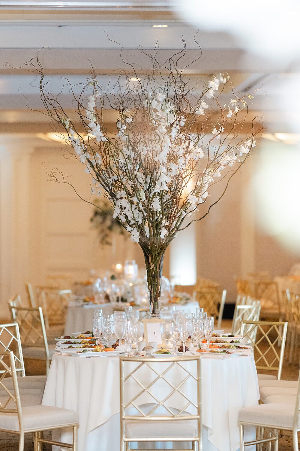 A towering white-blossom branch centerpiece anchors the reception table.