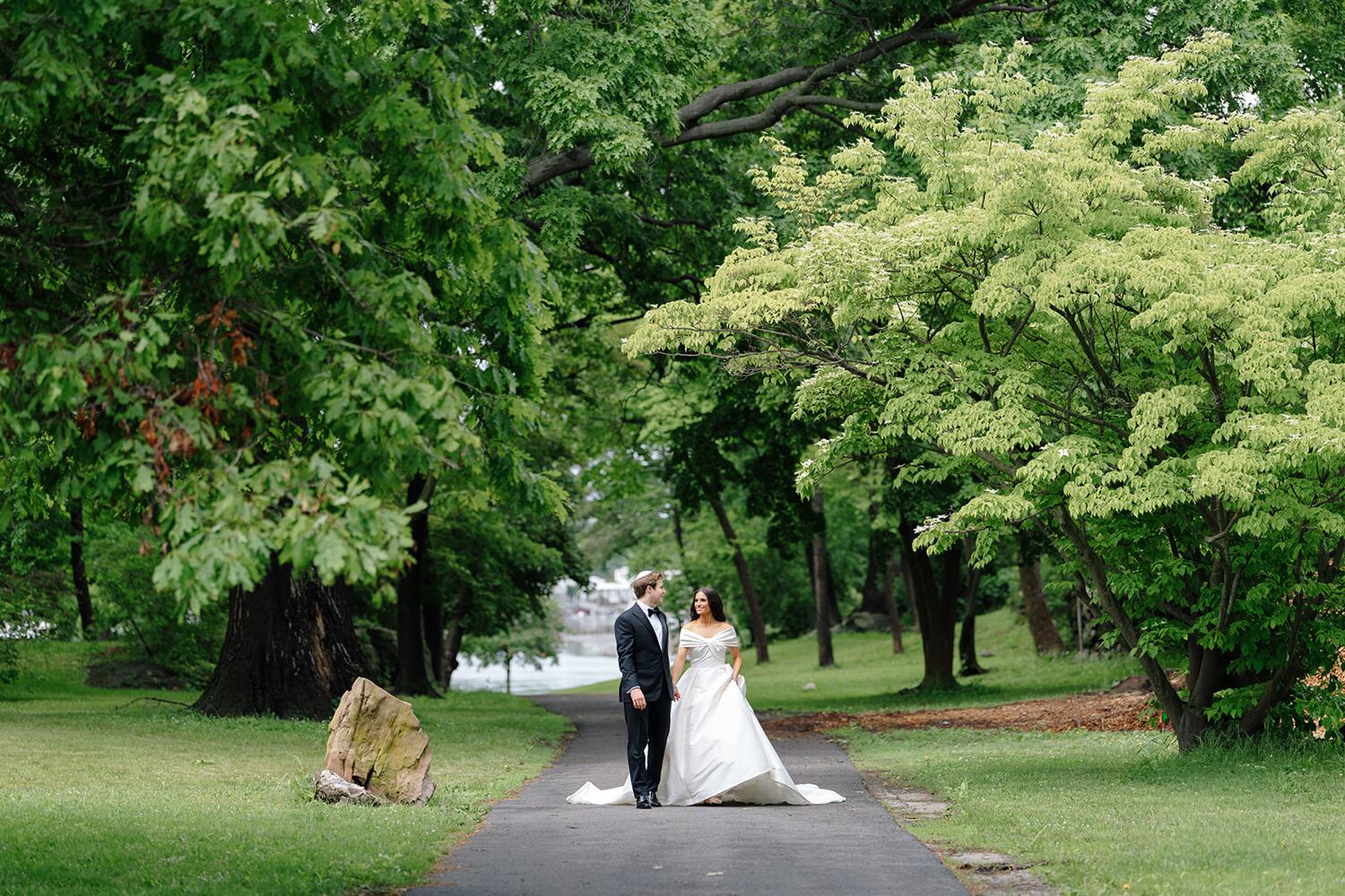 The couple appears small between towering trees on the island path.