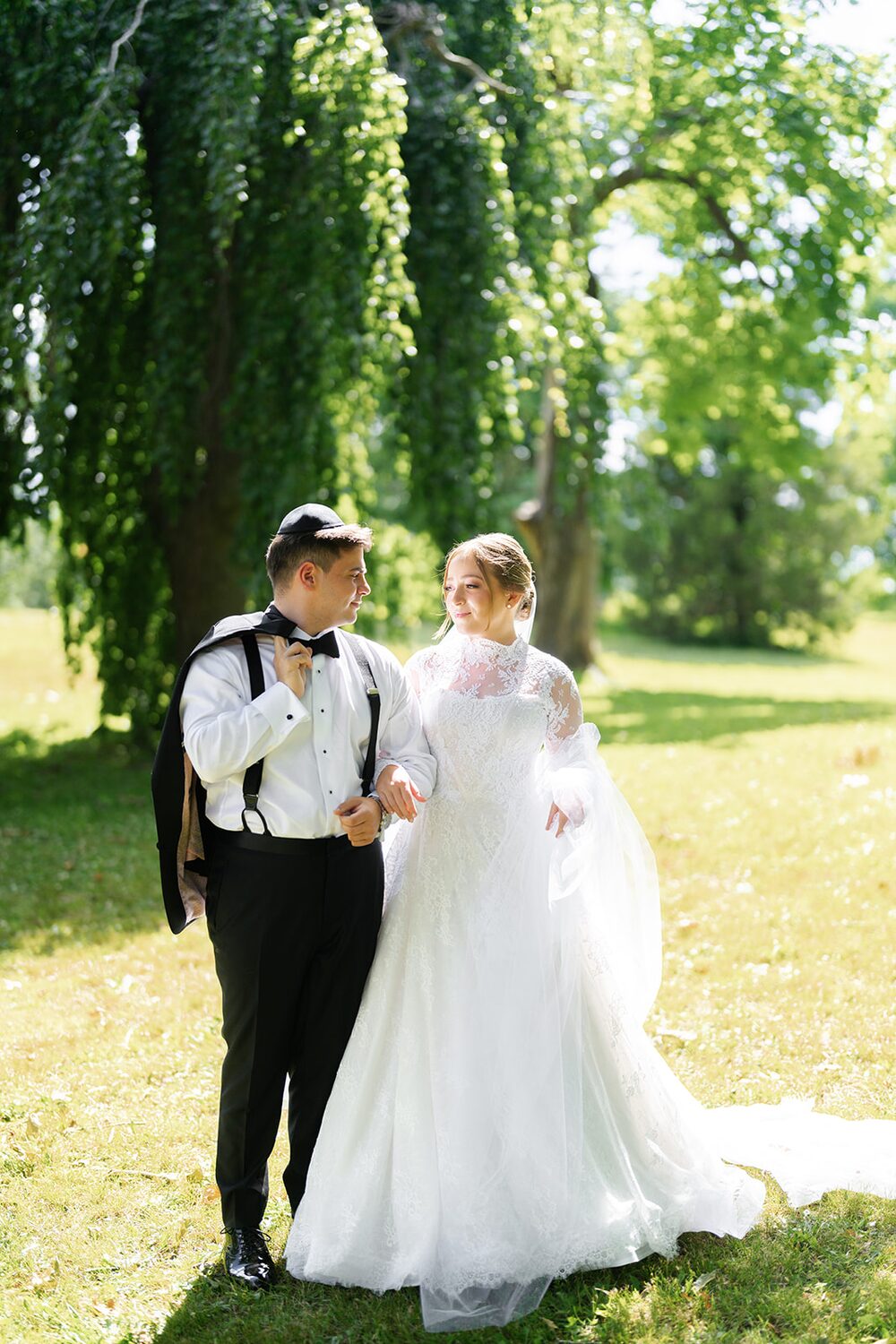 The couple strolls together beneath the willows on the island's park lawn.