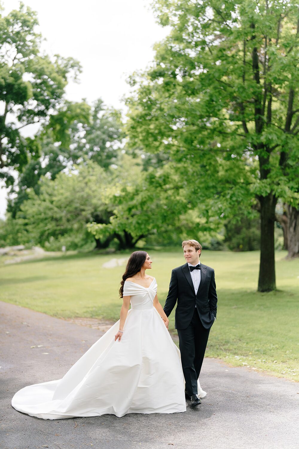Bride and groom walk the tree-lined path through Glen Island's park after their first look.