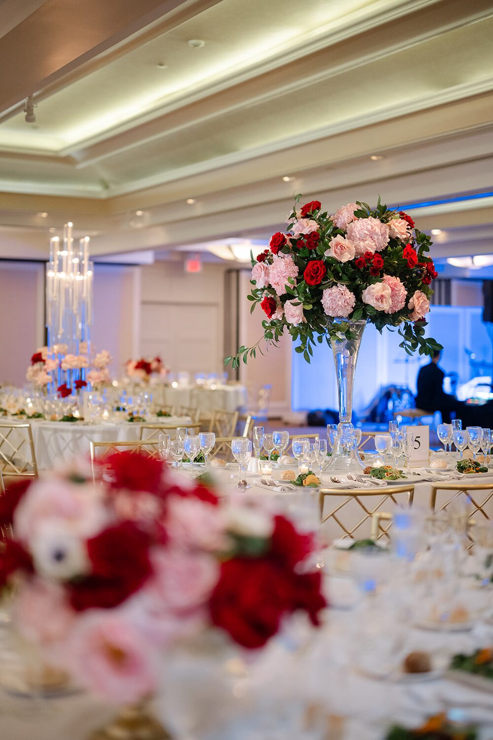Tall crimson and blush centerpieces set a rich late-autumn palette in the reception room.
