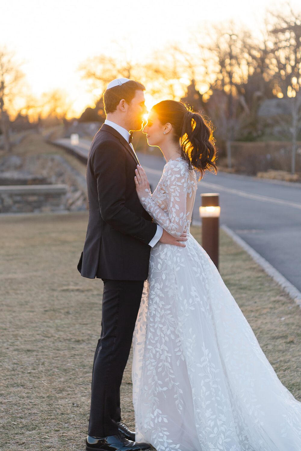 Backlit by a golden March sunset, the couple stands forehead to forehead.